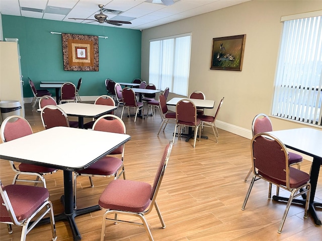 dining room with light wood-type flooring, ceiling fan, and a paneled ceiling