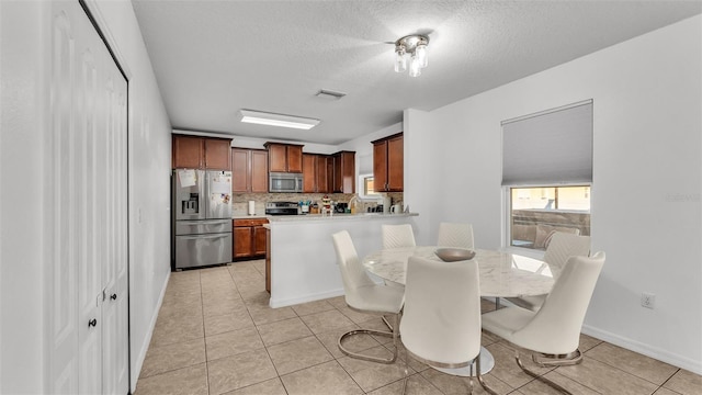 dining area featuring light tile patterned floors, baseboards, visible vents, and a textured ceiling