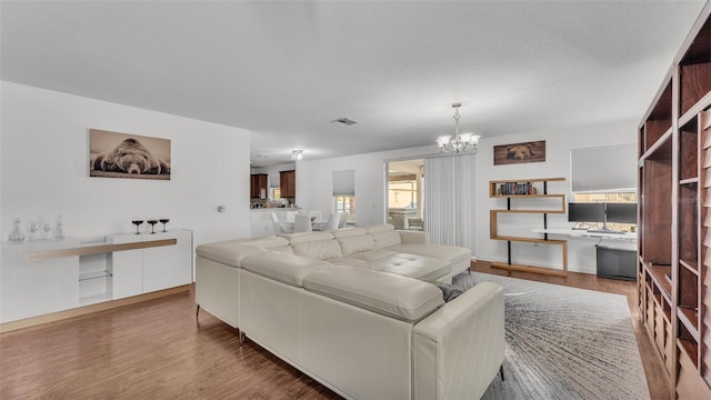 living area with visible vents, a notable chandelier, and wood finished floors