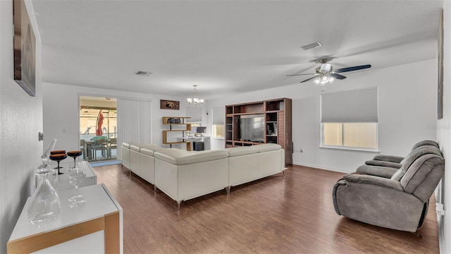 living room with visible vents, ceiling fan with notable chandelier, baseboards, and wood finished floors