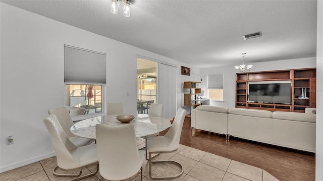 dining room featuring baseboards, visible vents, tile patterned flooring, a textured ceiling, and a chandelier