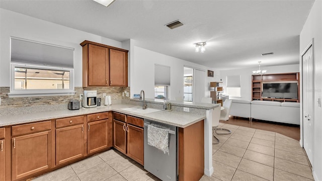 kitchen featuring light tile patterned floors, visible vents, a sink, stainless steel dishwasher, and brown cabinets