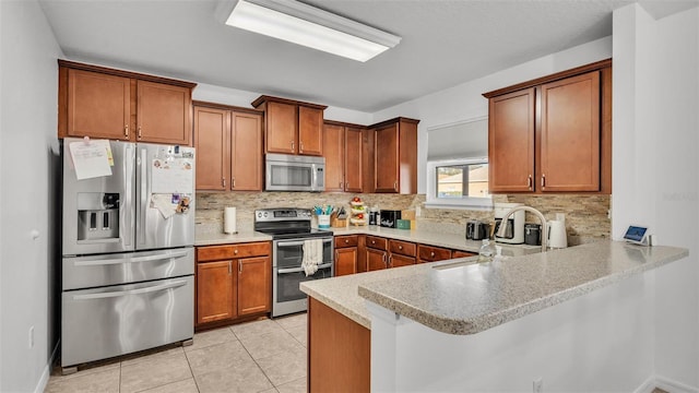 kitchen featuring light tile patterned floors, decorative backsplash, brown cabinets, a peninsula, and stainless steel appliances