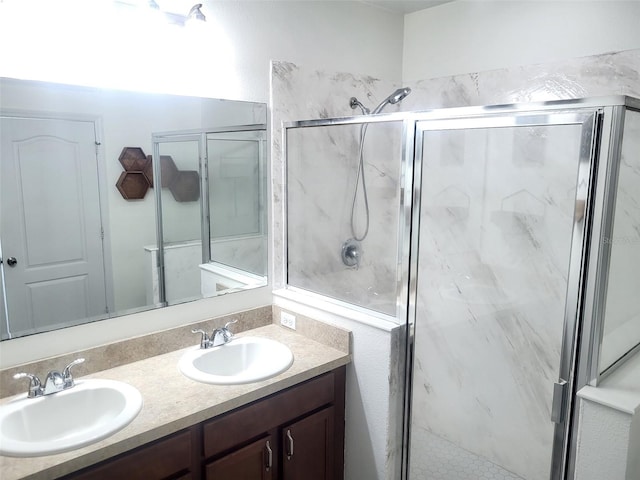 full bath with a marble finish shower, double vanity, and a sink