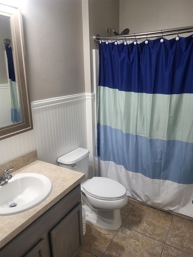 bathroom featuring wainscoting, curtained shower, vanity, and toilet