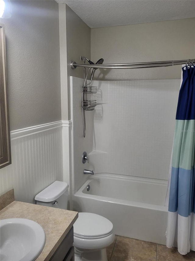 full bath featuring toilet, shower / tub combo with curtain, a textured ceiling, tile patterned flooring, and vanity