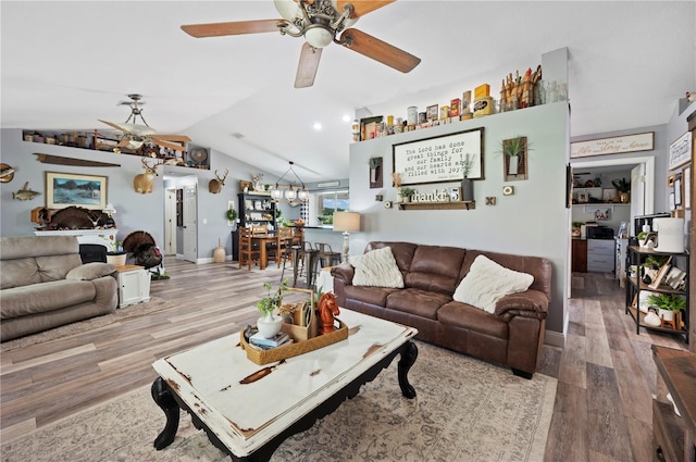 living room featuring hardwood / wood-style flooring, lofted ceiling, and ceiling fan with notable chandelier