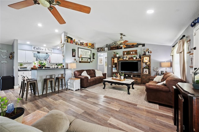 living room featuring ceiling fan, lofted ceiling, and light hardwood / wood-style floors