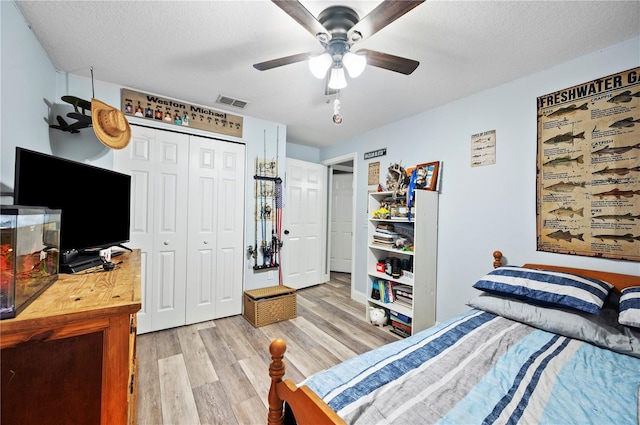 bedroom featuring a textured ceiling, light hardwood / wood-style floors, a closet, and ceiling fan