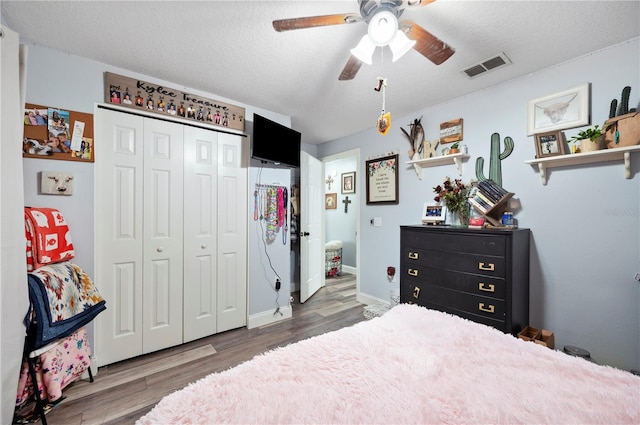 bedroom with ceiling fan, dark hardwood / wood-style floors, a closet, and a textured ceiling