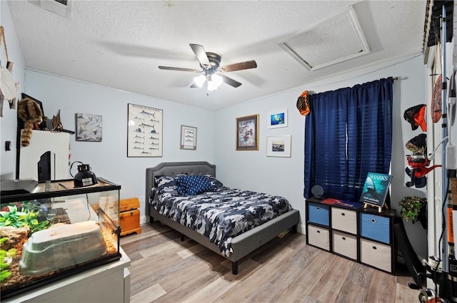 bedroom featuring ceiling fan, light hardwood / wood-style floors, and a textured ceiling