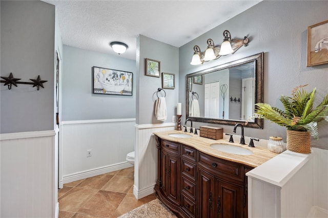 bathroom with tile patterned flooring, vanity, a textured ceiling, and toilet