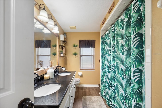 bathroom with toilet, a shower with curtain, a textured ceiling, vanity, and hardwood / wood-style flooring