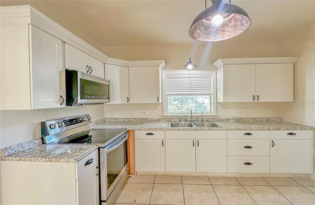 kitchen with sink, hanging light fixtures, light tile patterned flooring, white cabinets, and appliances with stainless steel finishes