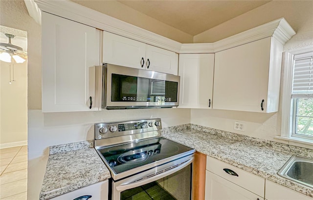 kitchen featuring light stone countertops, white cabinetry, ceiling fan, stainless steel appliances, and light tile patterned flooring