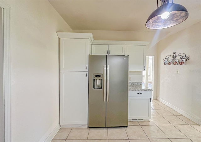 kitchen featuring white cabinetry, stainless steel fridge with ice dispenser, light tile patterned floors, and light stone counters