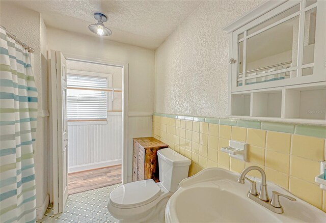 bathroom with hardwood / wood-style floors, a textured ceiling, toilet, and sink