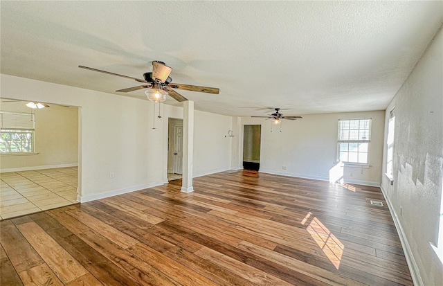 unfurnished living room with ceiling fan, hardwood / wood-style floors, and a textured ceiling