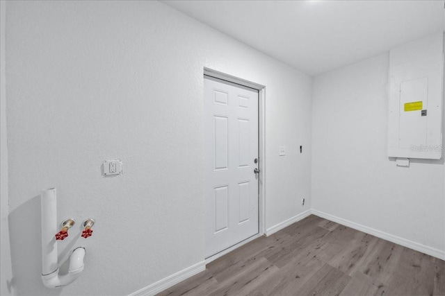 clothes washing area featuring electric panel and light hardwood / wood-style flooring