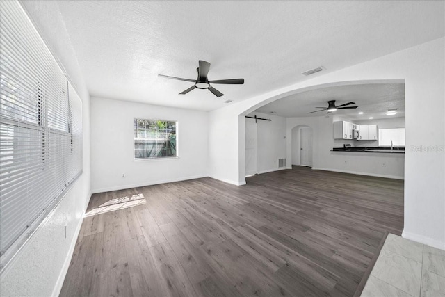 unfurnished living room with a textured ceiling, dark hardwood / wood-style floors, ceiling fan, and sink