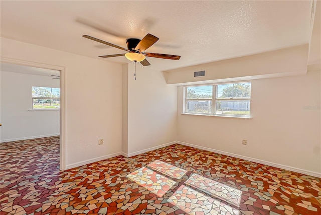 spare room featuring a textured ceiling, ceiling fan, and a healthy amount of sunlight