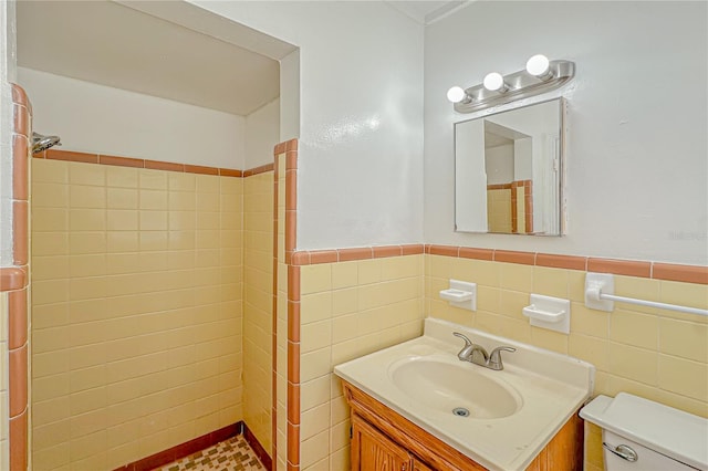 bathroom featuring a tile shower, vanity, toilet, and tile walls