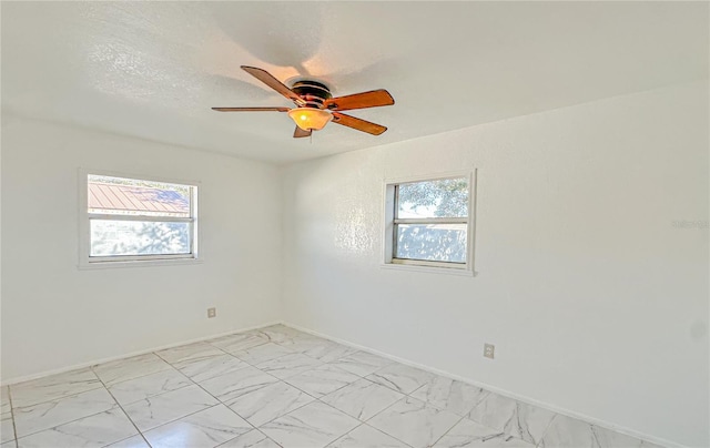 spare room with a textured ceiling, a wealth of natural light, and ceiling fan