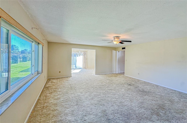 unfurnished room with ceiling fan with notable chandelier, light colored carpet, and a textured ceiling