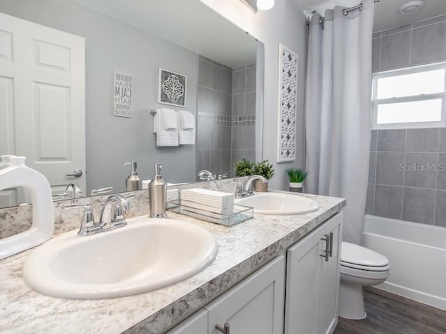 full bathroom featuring hardwood / wood-style floors, vanity, shower / tub combo, and toilet