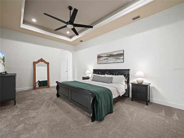 carpeted bedroom with a tray ceiling, ceiling fan, and ornamental molding