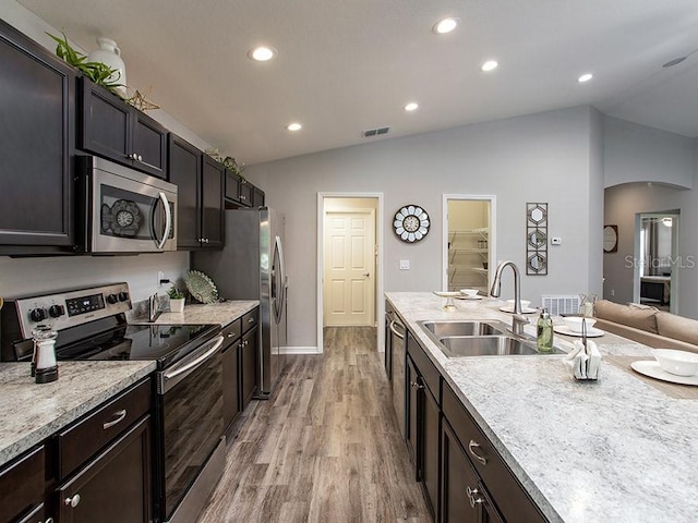 kitchen featuring light wood-type flooring, sink, appliances with stainless steel finishes, and vaulted ceiling