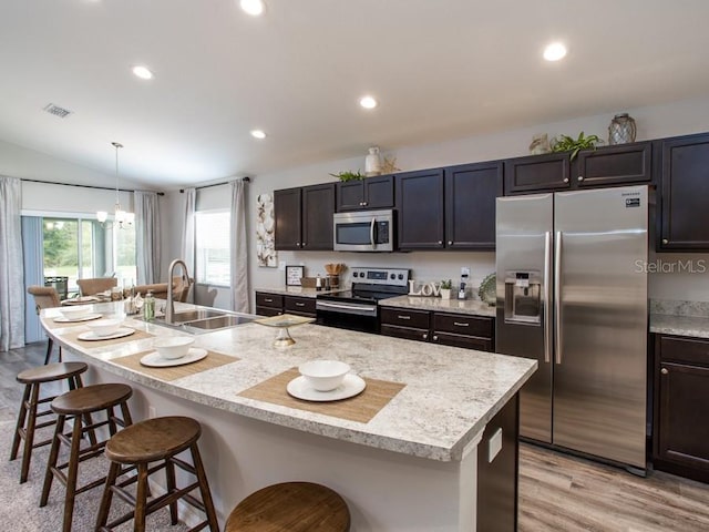 kitchen with stainless steel appliances, sink, decorative light fixtures, a breakfast bar area, and an island with sink