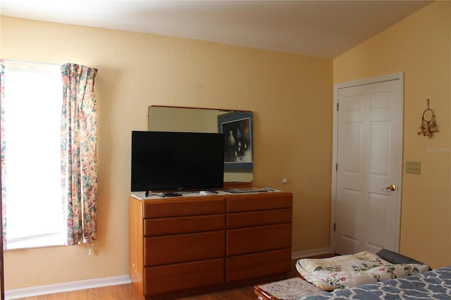 bedroom with hardwood / wood-style flooring and lofted ceiling