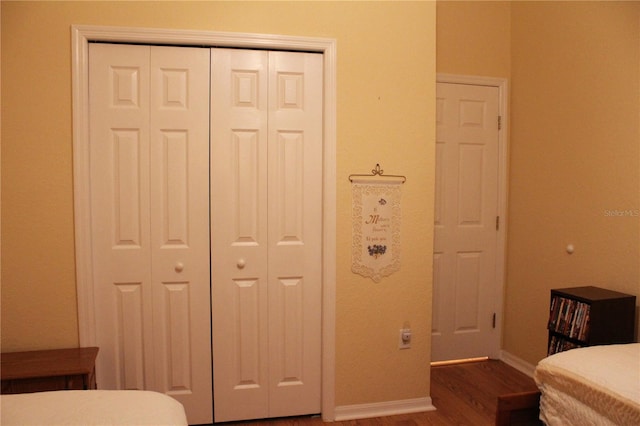 bedroom with dark hardwood / wood-style flooring and a closet