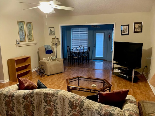 living room with hardwood / wood-style flooring, ceiling fan, lofted ceiling, and a textured ceiling