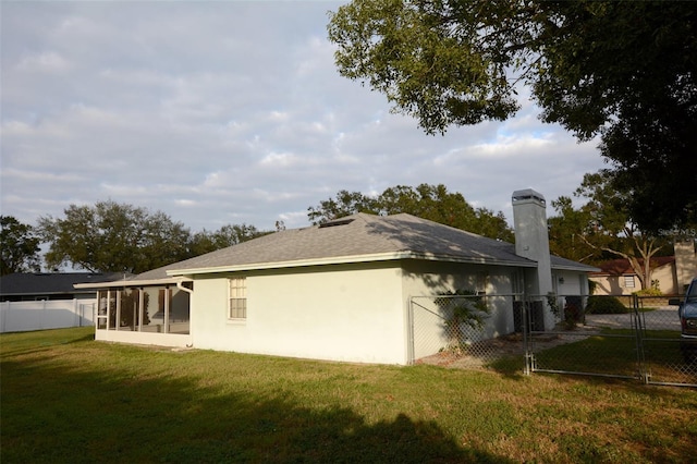 back of property featuring a lawn and a sunroom