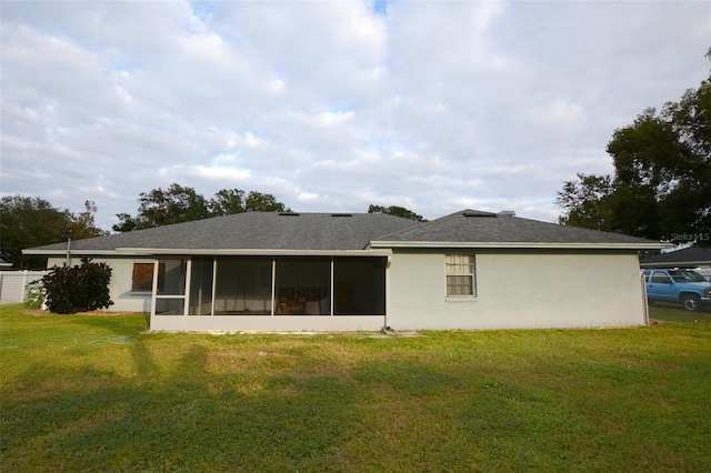 rear view of property featuring a sunroom and a yard