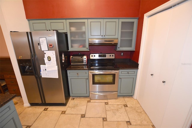 kitchen with gray cabinets, stainless steel appliances, and dark stone counters