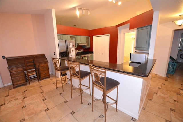 kitchen featuring kitchen peninsula, a breakfast bar, green cabinetry, and appliances with stainless steel finishes