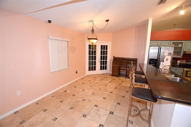 kitchen featuring french doors, a breakfast bar, stainless steel appliances, sink, and hanging light fixtures