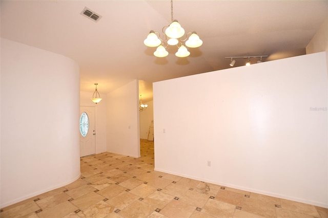 empty room with vaulted ceiling and a notable chandelier