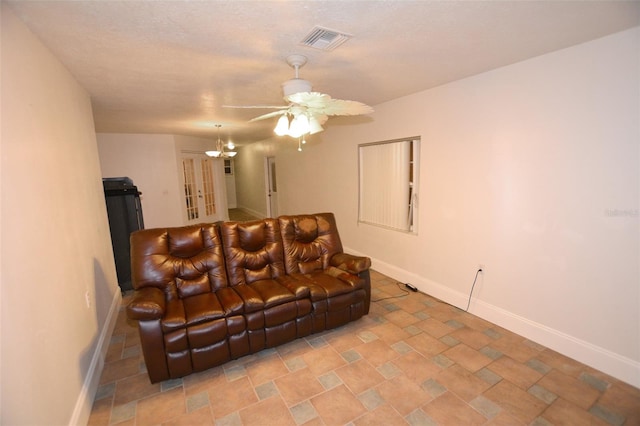 living room with ceiling fan with notable chandelier and a textured ceiling