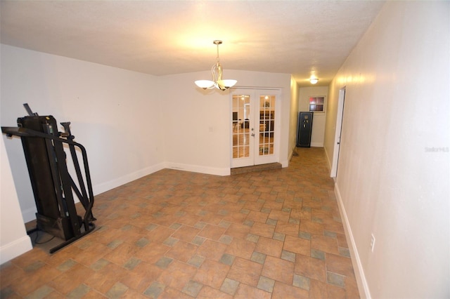 empty room featuring french doors and a notable chandelier