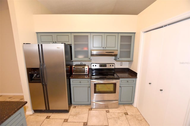 2556 Roslyn Ln, Lakeland, FL 33812 - kitchen with under cabinet range hood, dark stone countertops, gray cabinets, glass insert cabinets, and appliances with stainless steel finishes