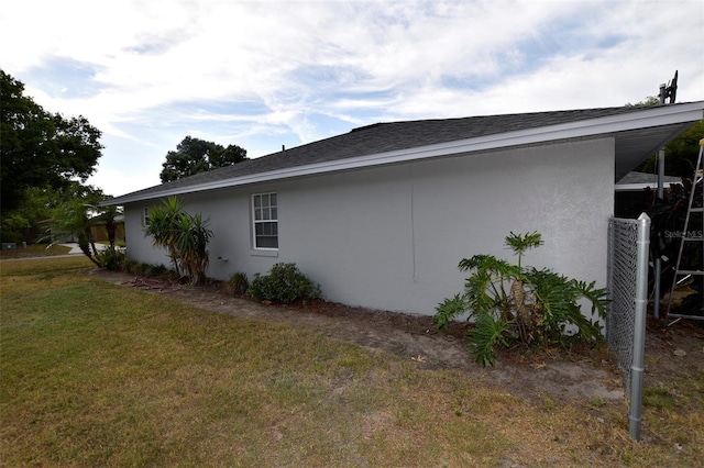 2556 Roslyn Ln, Lakeland, FL 33812 - view of side of property with stucco siding, roof with shingles, and a lawn