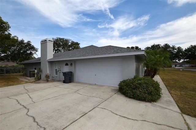2556 Roslyn Ln, Lakeland, FL 33812 - view of home's exterior featuring driveway, a chimney, a garage, a shingled roof, and stucco siding