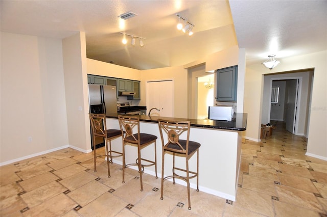2556 Roslyn Ln, Lakeland, FL 33812 - kitchen featuring under cabinet range hood, stainless steel appliances, dark countertops, visible vents, and a kitchen bar