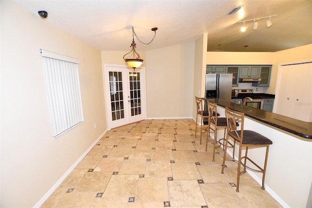 2556 Roslyn Ln, Lakeland, FL 33812 - kitchen with a kitchen breakfast bar, french doors, dark countertops, under cabinet range hood, and appliances with stainless steel finishes