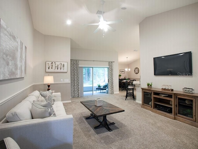 carpeted living room with ceiling fan with notable chandelier and vaulted ceiling