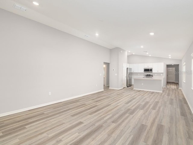 unfurnished living room featuring vaulted ceiling and light hardwood / wood-style floors